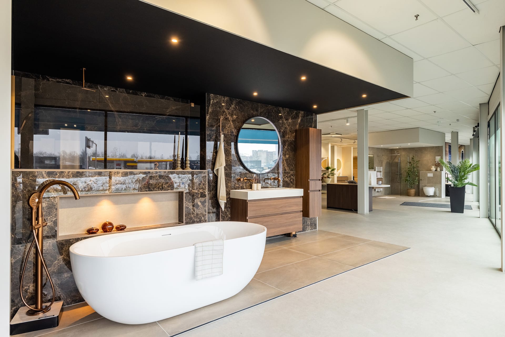 Luxe badkamer met een vrijstaand wit bad, marmeren wanden en een houten badmeubel.