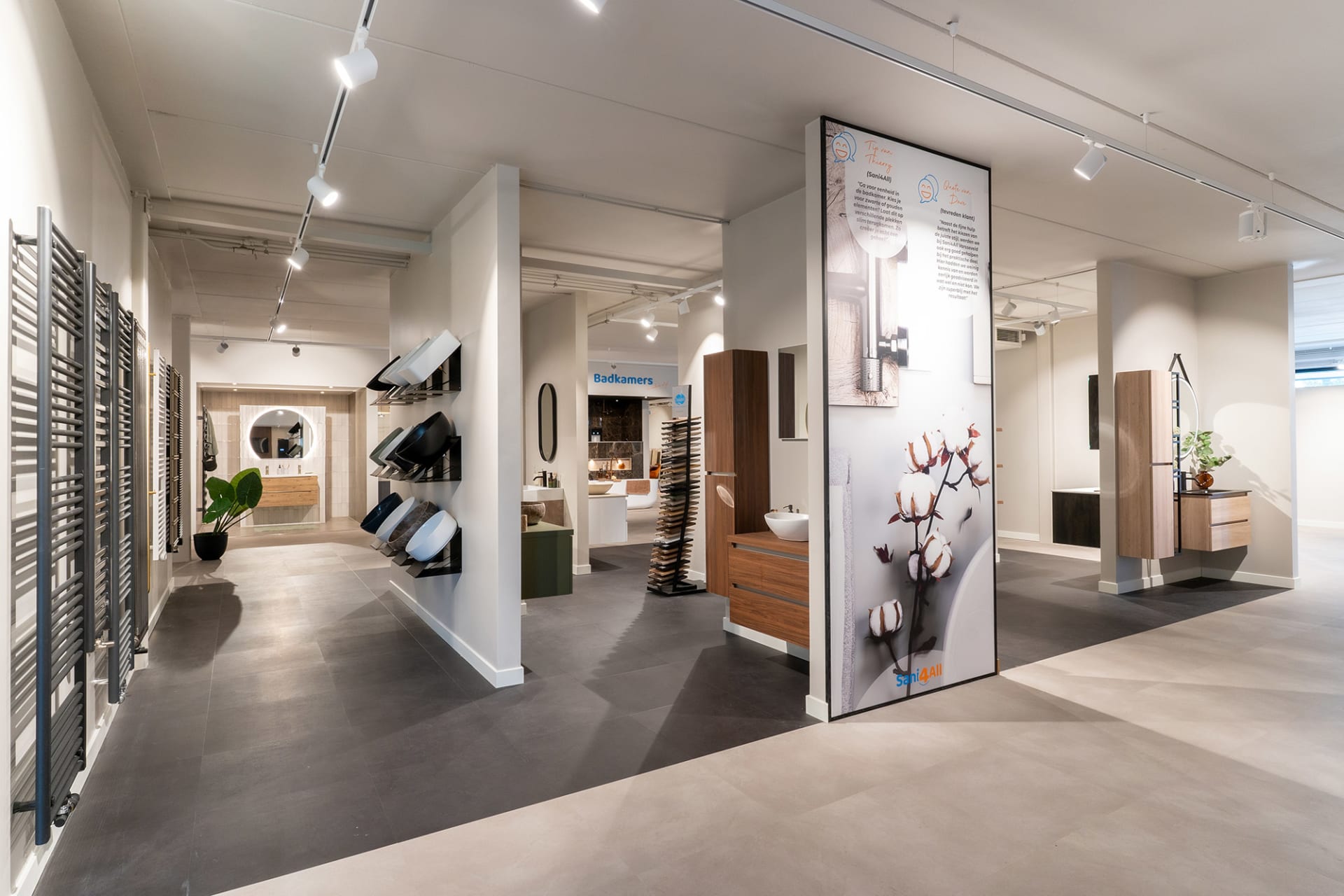 Overzicht van de Sani4All winkel met diverse badkameropstellingen en inspiratieborden.