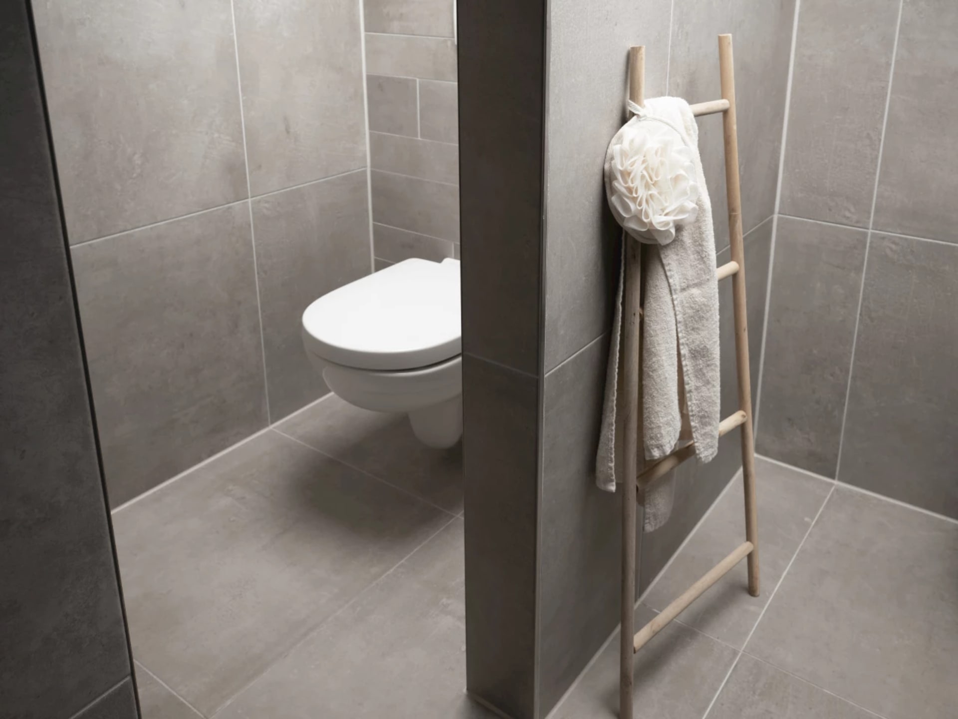 Wit hangend wandcloset in de aparte toilethoek, met een houten handdoekladder ernaast