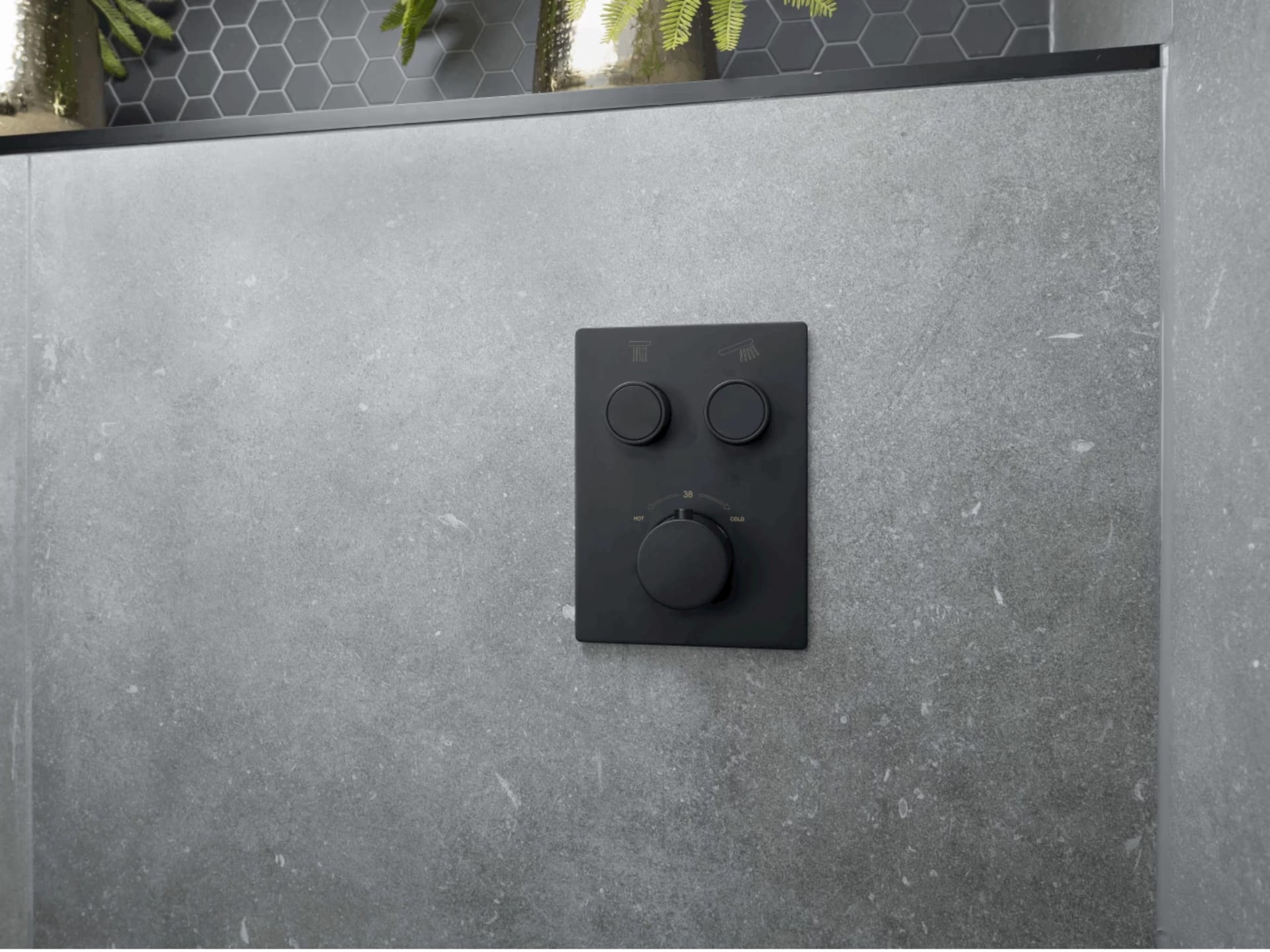 Mat zwarte inbouwbediening met twee drukknoppen en een thermostaatknop op de betonlook wand