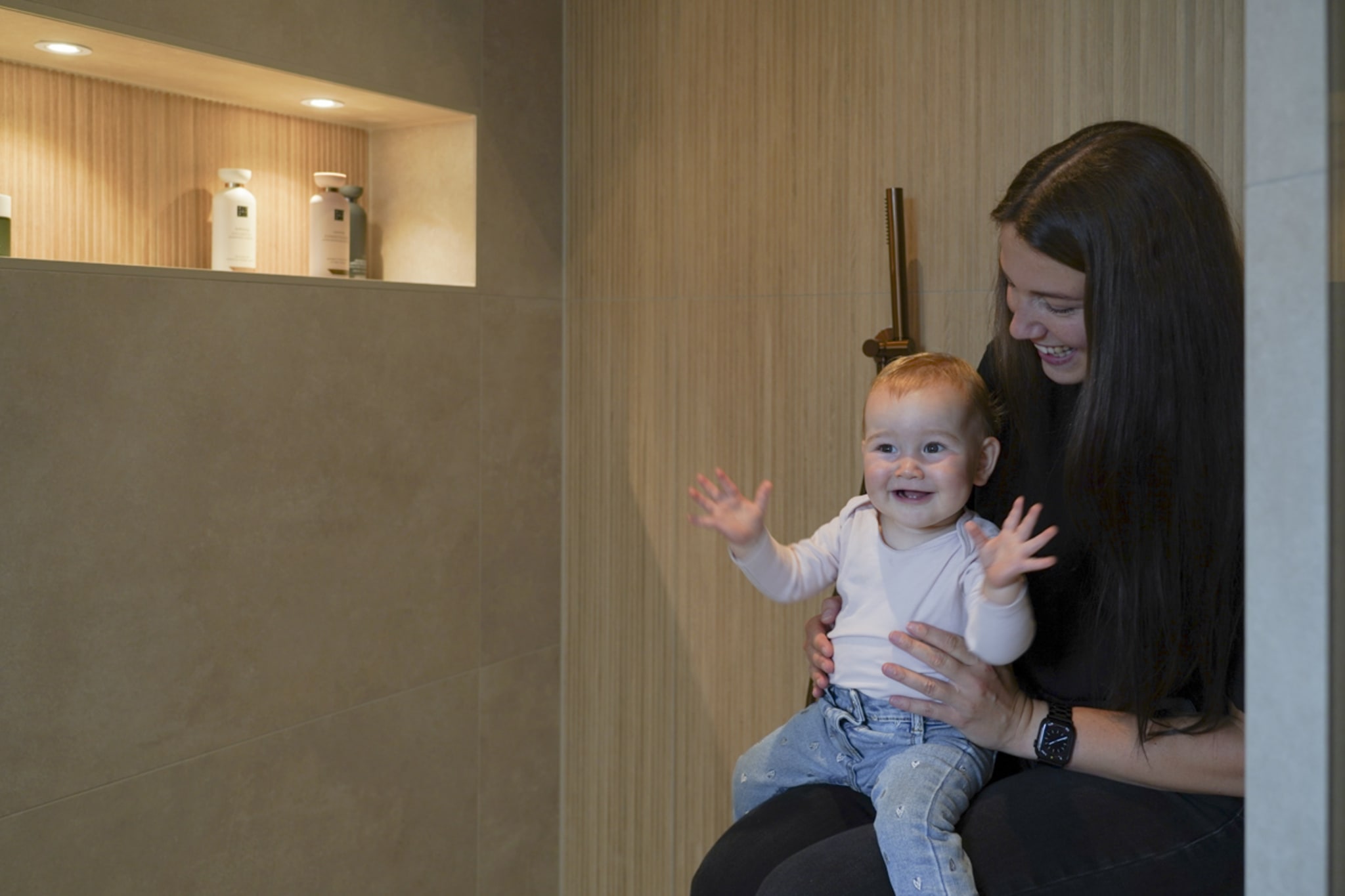 Doreen en Sophie op het bankje in de inloopdouche, naast de verlichte nis met houtlook tegels