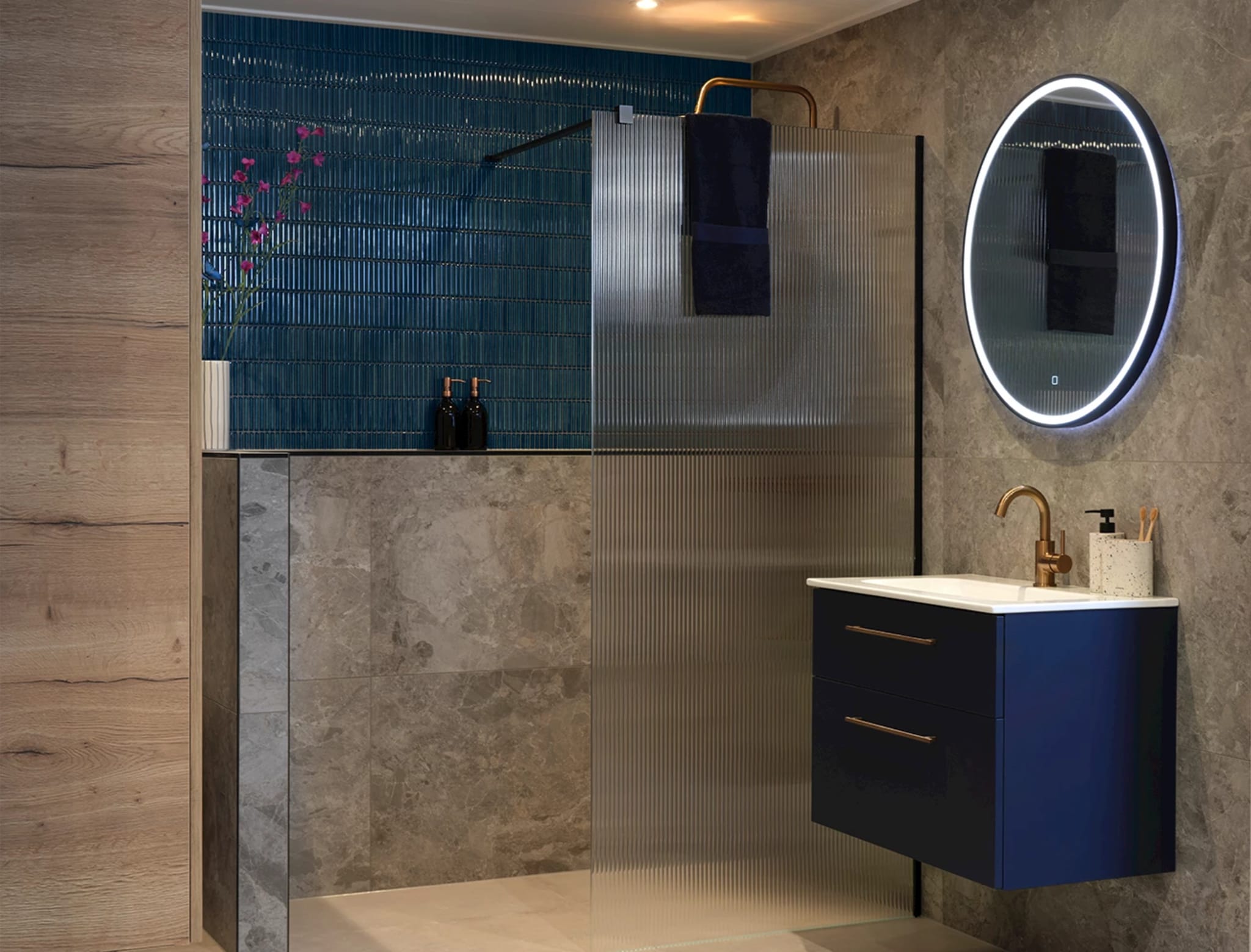 Blauw badmeubel met witte keramische wastafel, koperkleurige kraan en een ronde spiegel met ledverlichting