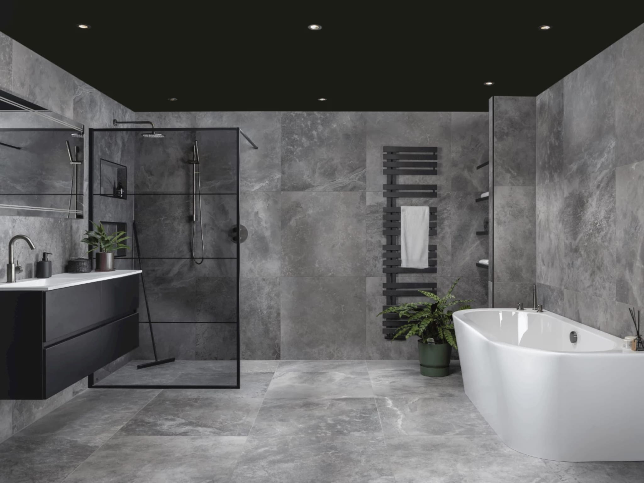 Complete badkamer Brushed Graphit met gemarmerde grijze tegels, mat zwart badmeubel, inloopdouche met zwart frame en een half vrijstaand ligbad