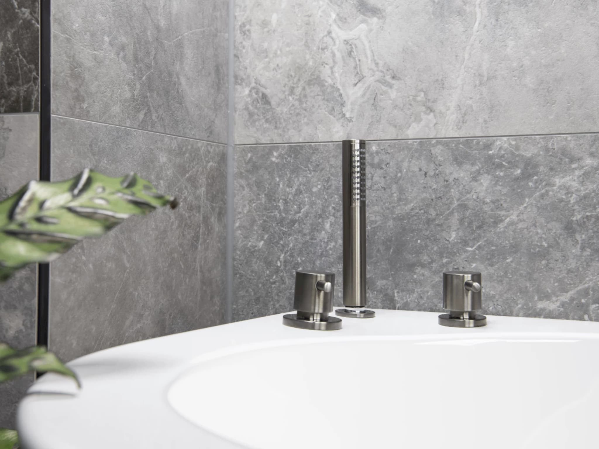 Inbouw badkraan in Brushed Graphit met uittrekbare handdouche op de rand van het witte ligbad