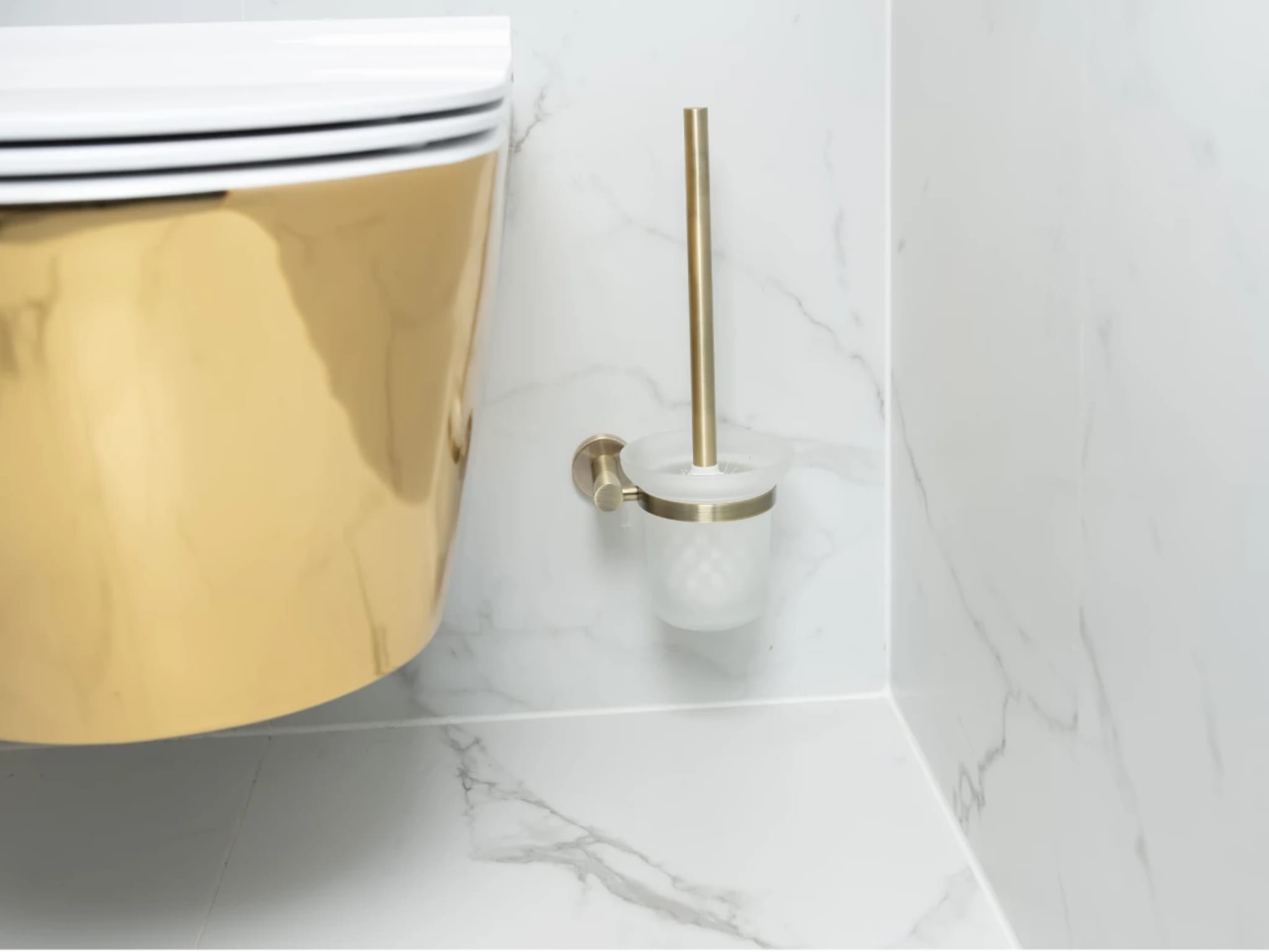Close-up van het goudkleurige wandcloset met een gouden toiletborstelhouder tegen de marmerlook wand