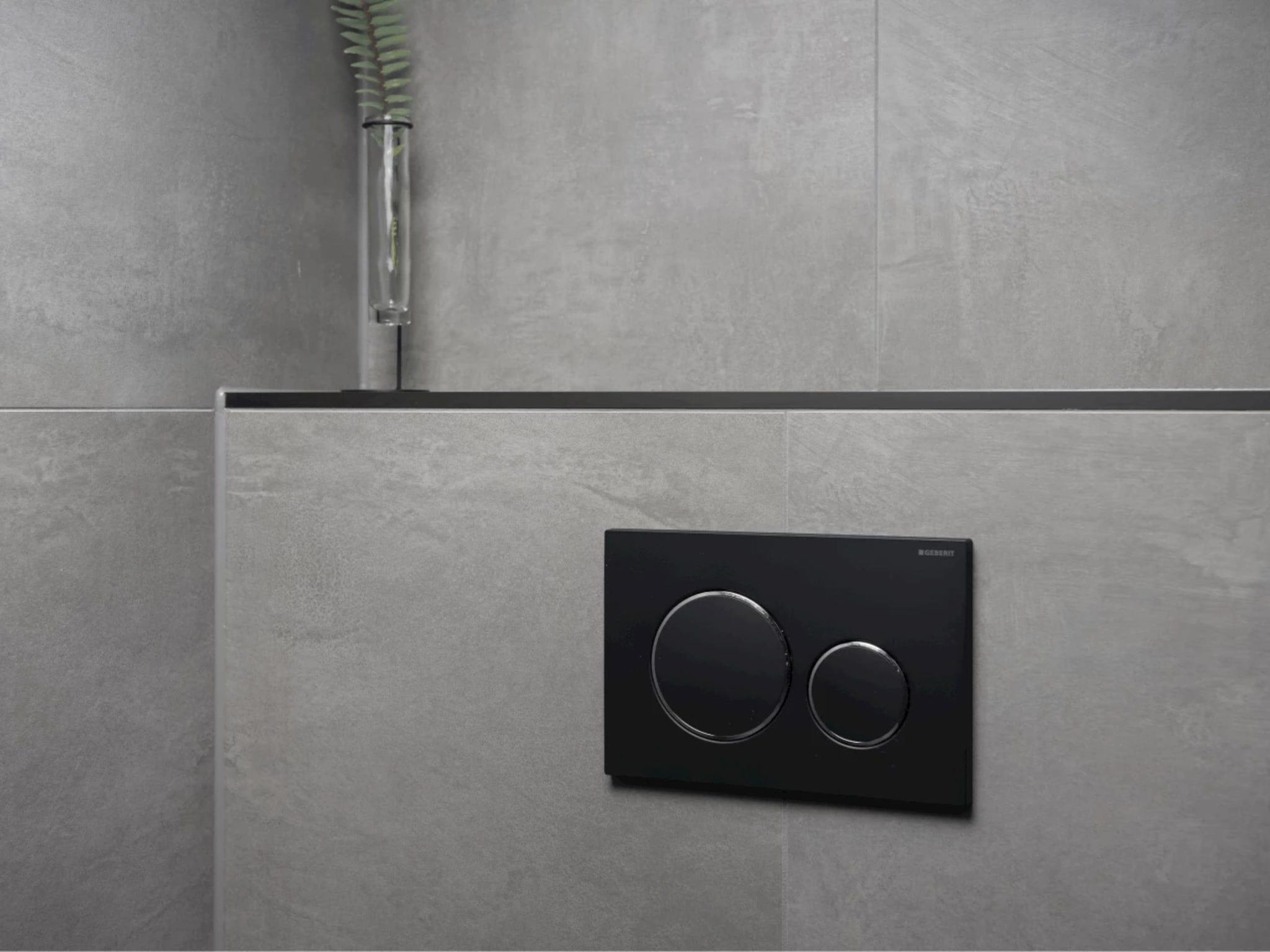Mat zwart Geberit-bedieningspaneel op grijze betonlook wandtegels in toilet Black Decor