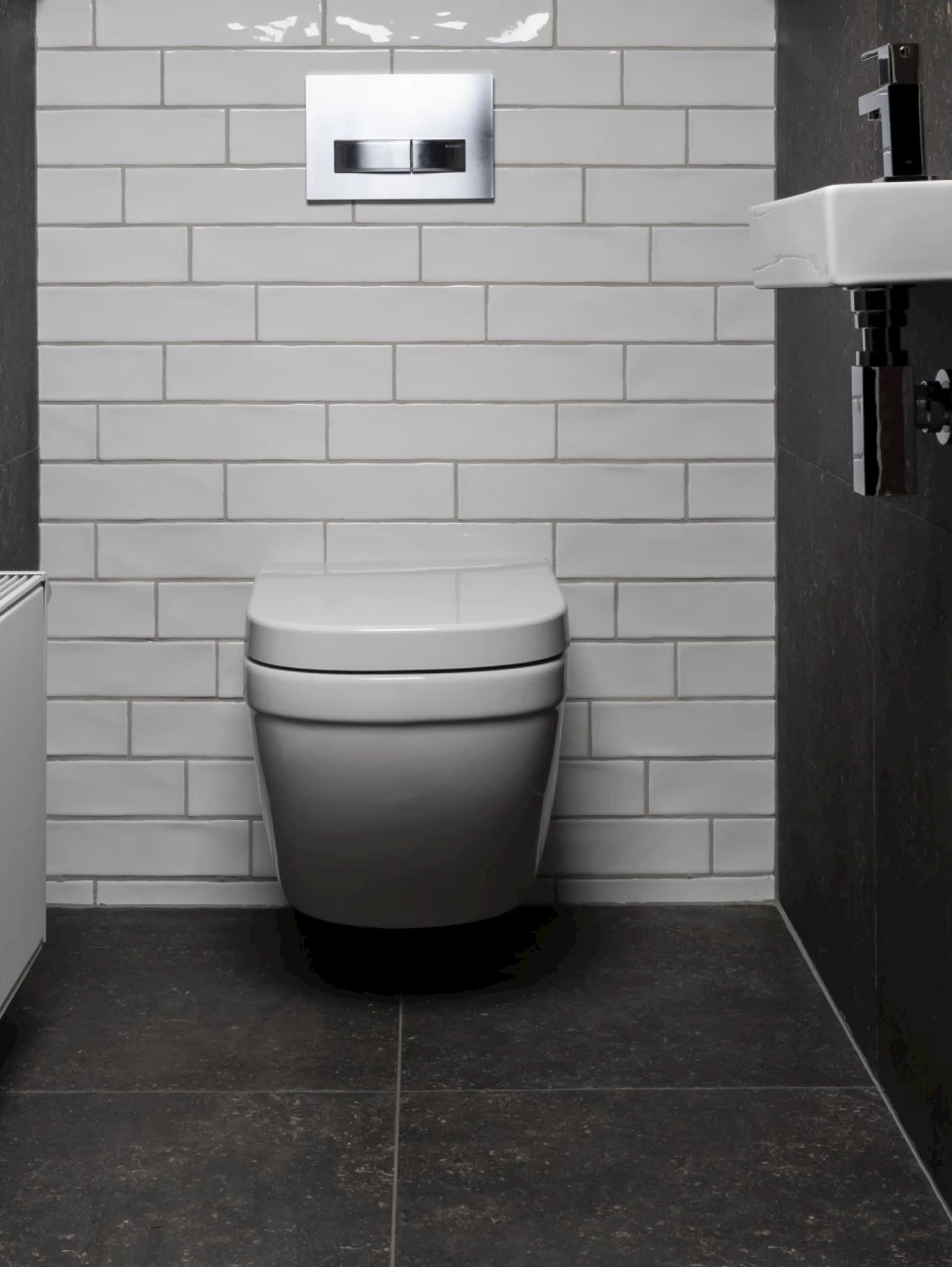 Compleet toilet Fresh Lines met een wit wandcloset tegen witte handgevormde tegels en een donkere terrazzolook vloer