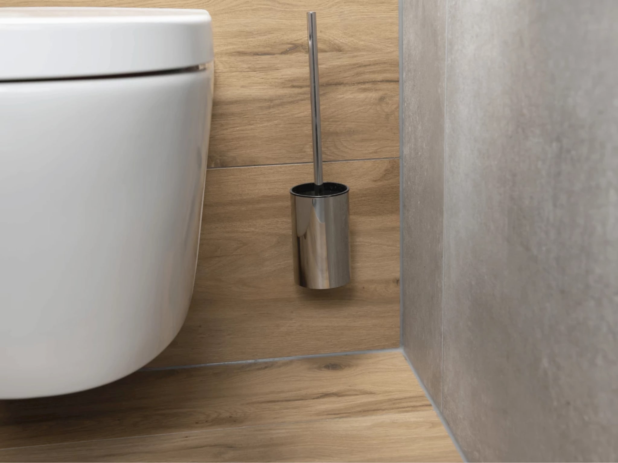 Close-up van het witte wandcloset met een toiletborstelhouder in rvs tegen de houtlook tegels