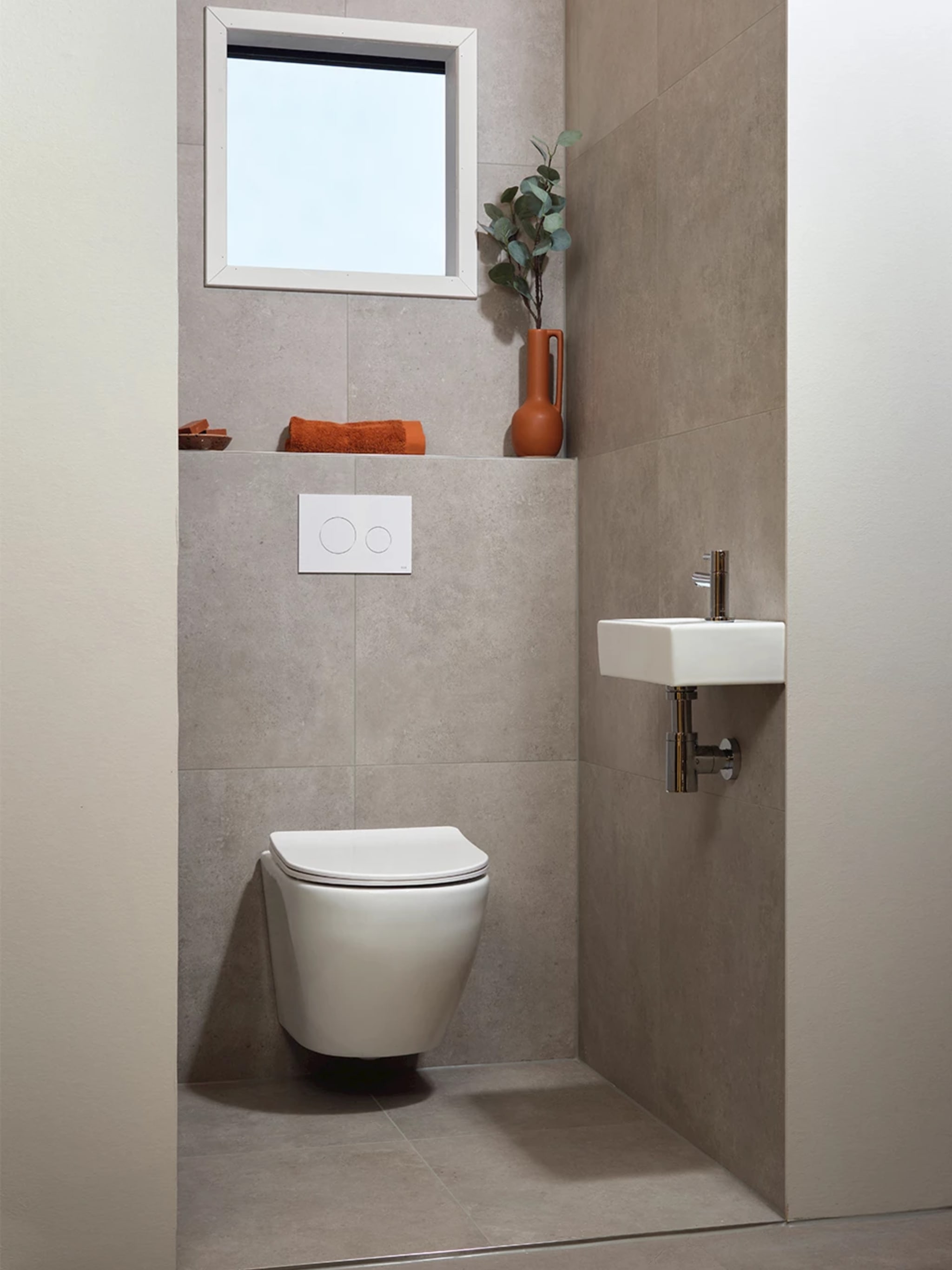 Compleet toilet Natural grey met grijsbeige betonlook tegels op vloer en wanden, een wit wandcloset en een klein fonteintje
