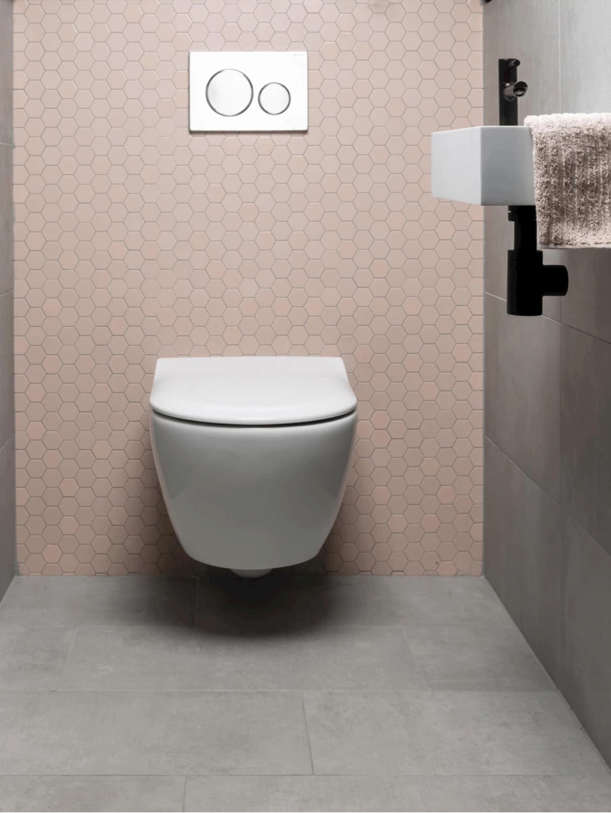 Compleet toilet Pink Beton met een achterwand van lichtroze hexagontegels, een wit wandcloset en lichtgrijze betonlook vloertegels