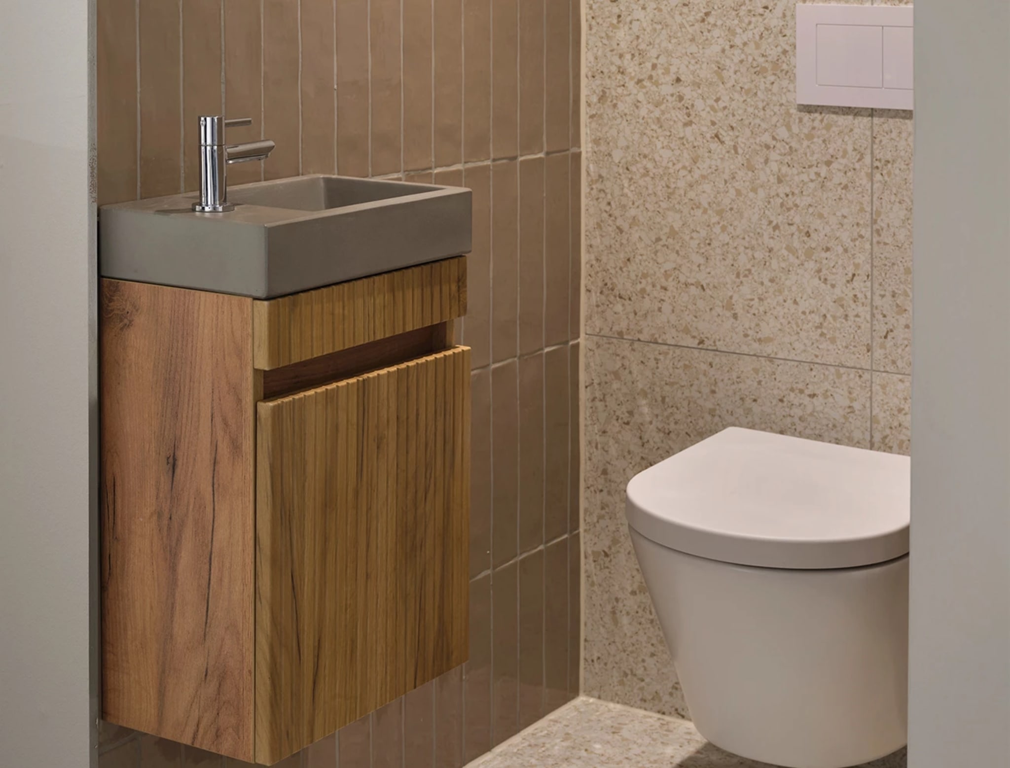 Houtkleurige fonteinkast met een geribbeld front, een betonlook fonteinbak en een chromen kraan bij Sani4All
