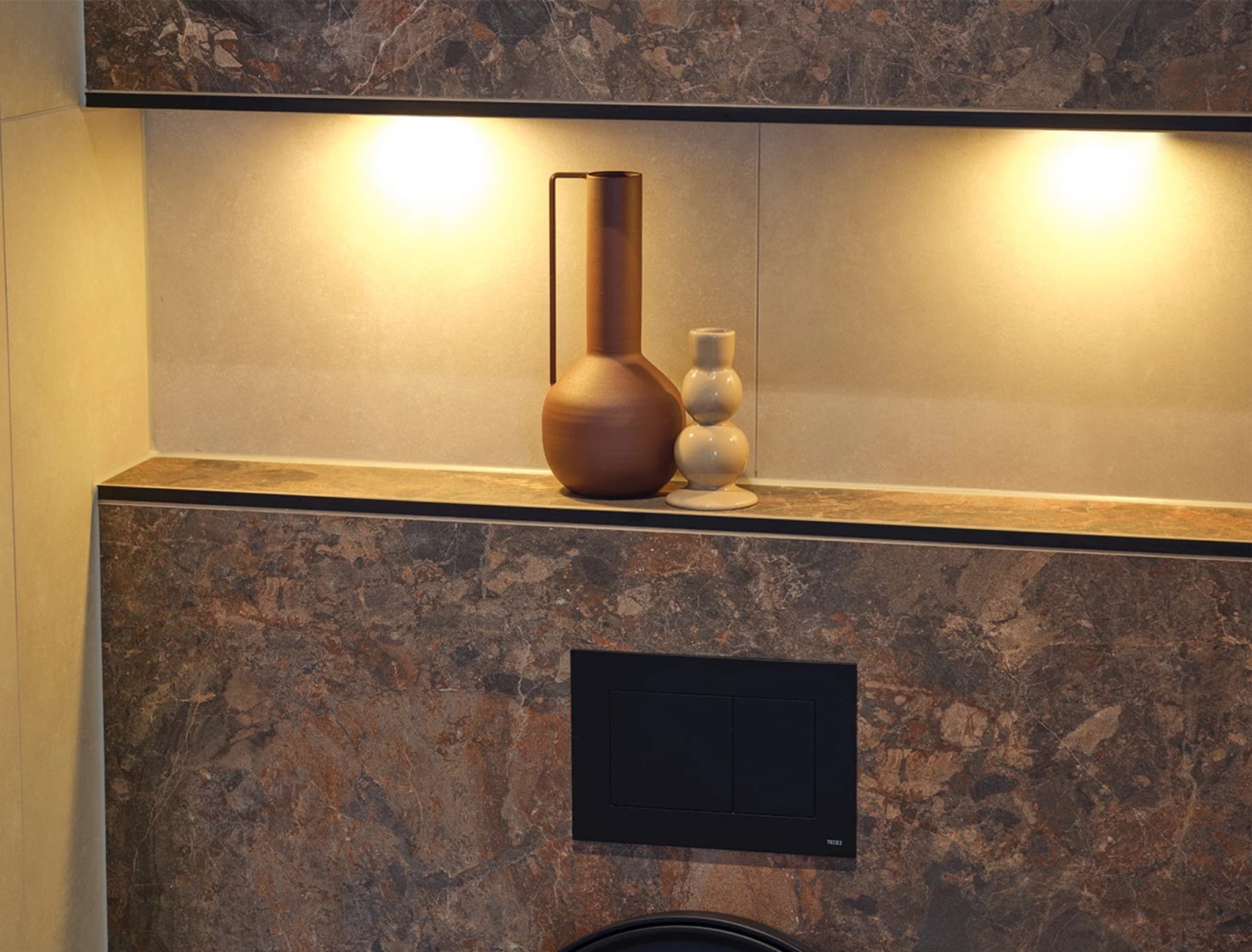Verlichte nis met twee ledspots, een terracotta vaas en een crèmekleurig vaasje, met het zwarte bedieningspaneel eronder