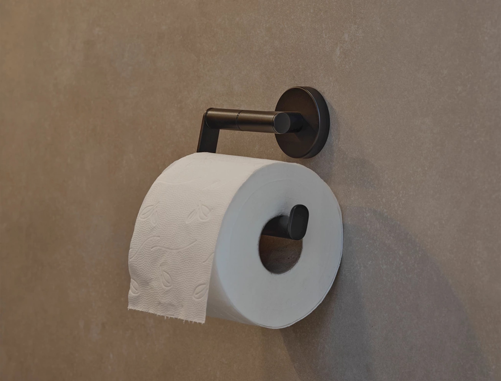 Donkere rolhouder met een witte rol op de zandkleurige wand