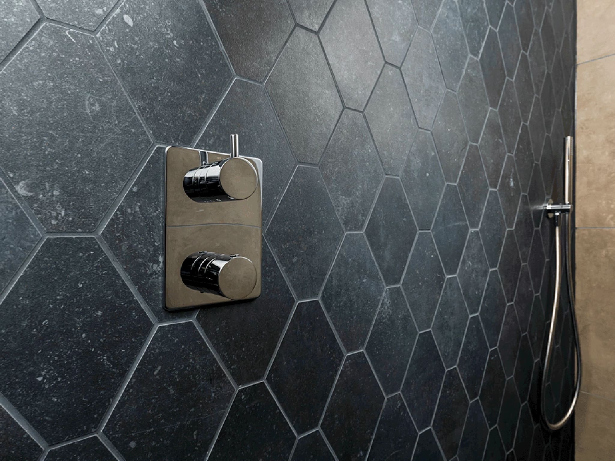 Close-up van de chromen inbouw douchethermostaat op de zwarte hexagontegels