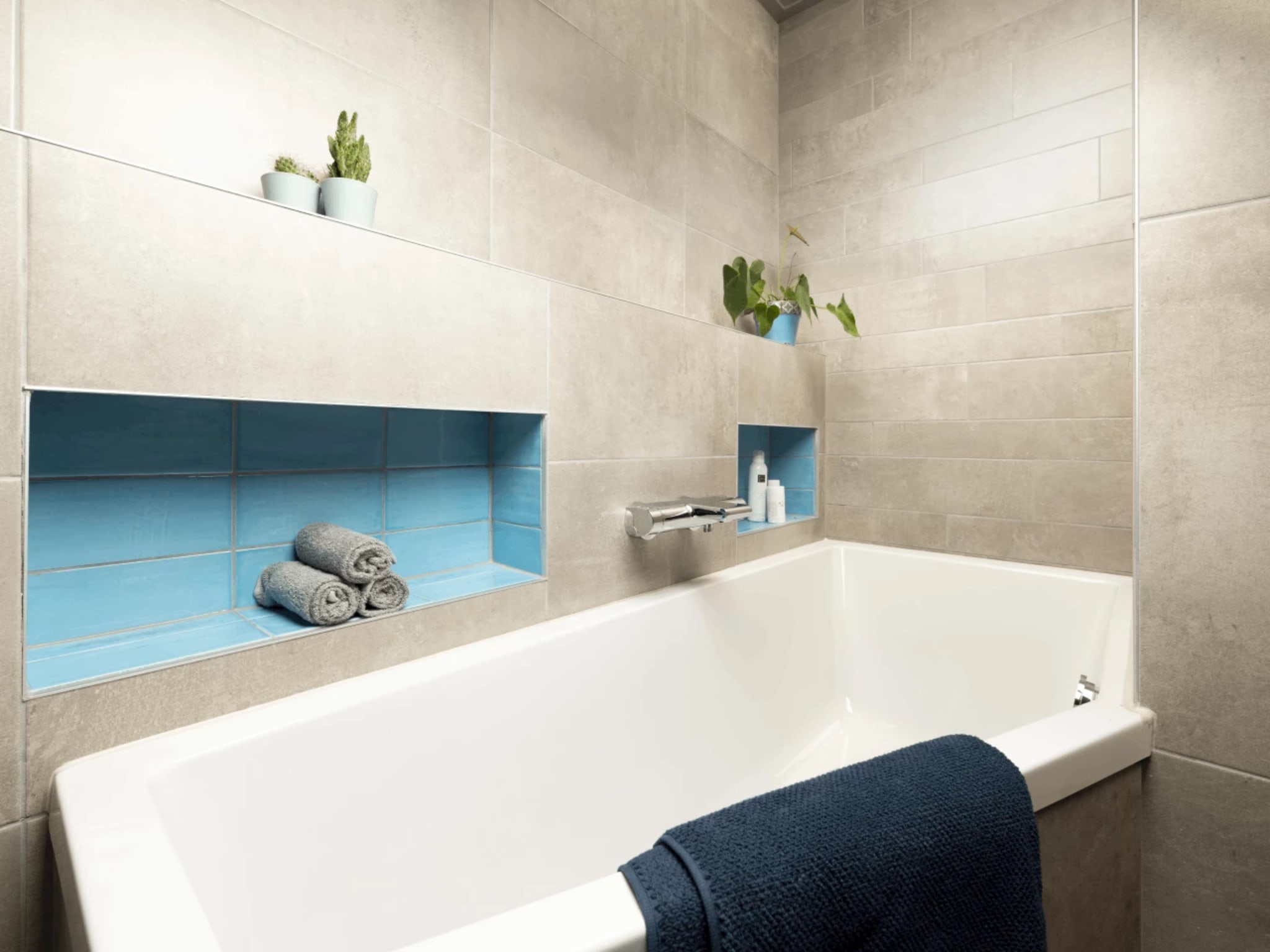 Ligbad met chromen badkraan en blauw betegelde nissen in badkamer Compact Blue