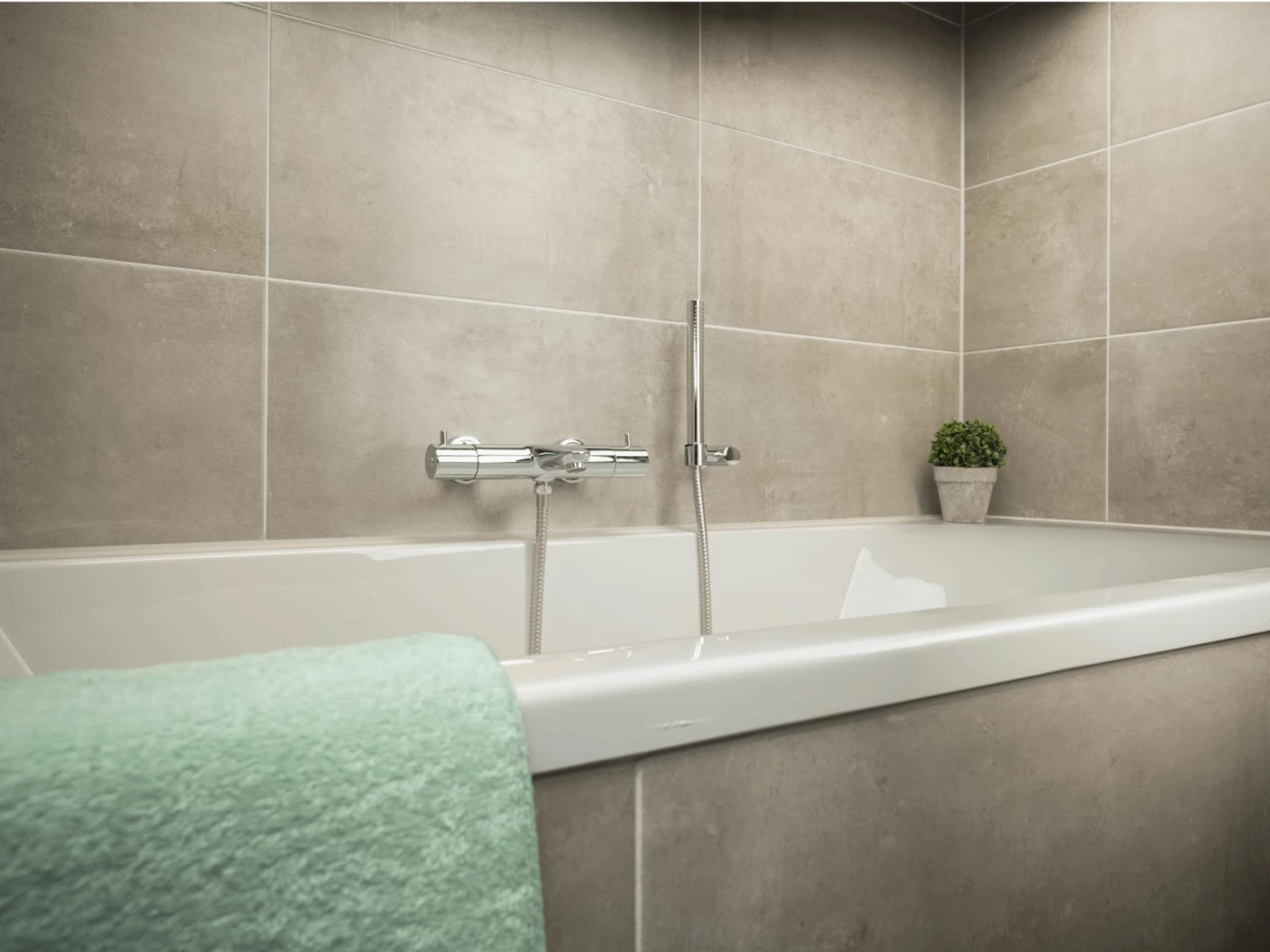 Het ingebouwde ligbad met chromen badkraan en losse handdouche tegen de grote betonlook wandtegels