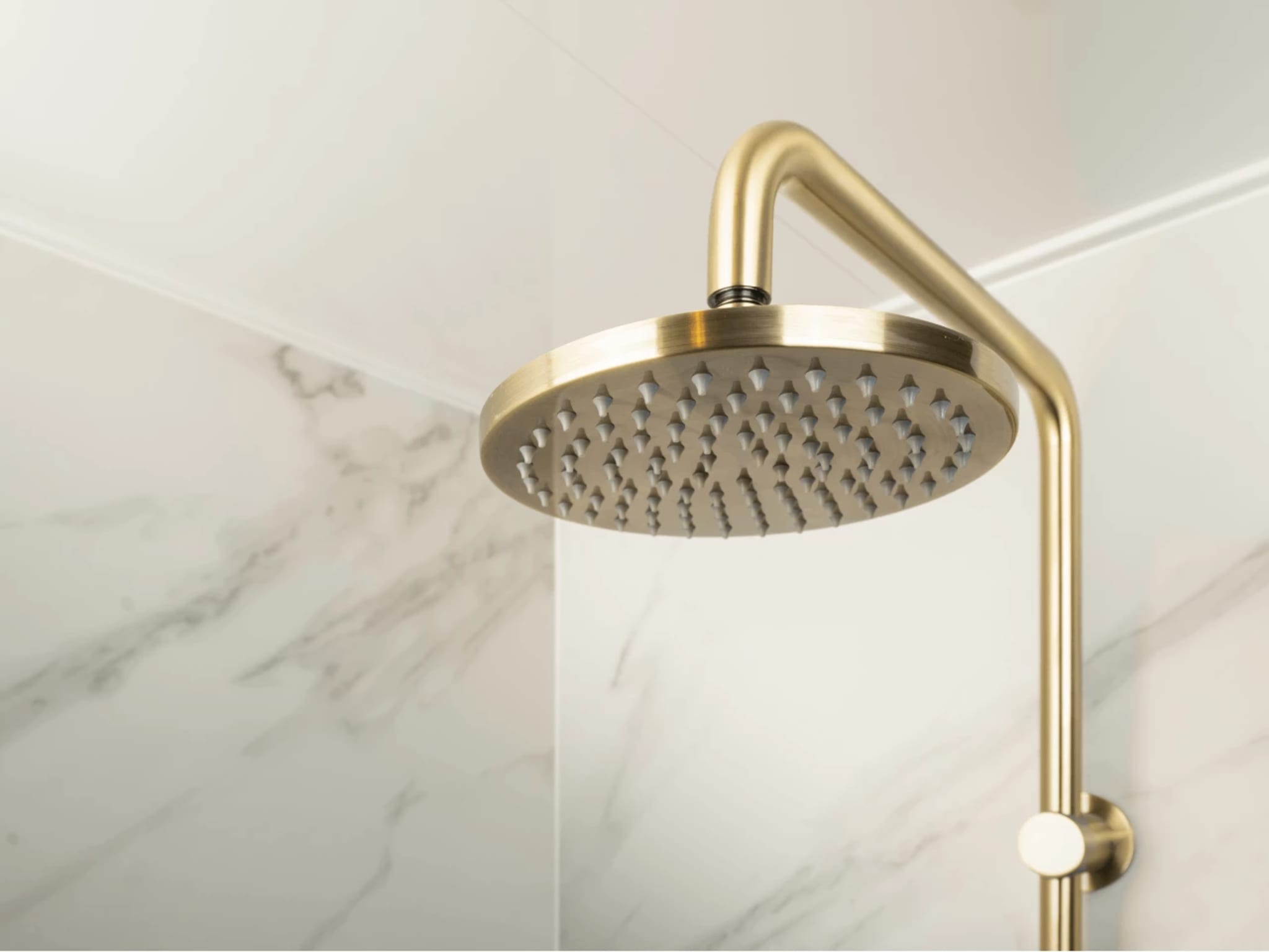 Geborsteld gouden regendouchekop in badkamer Marble