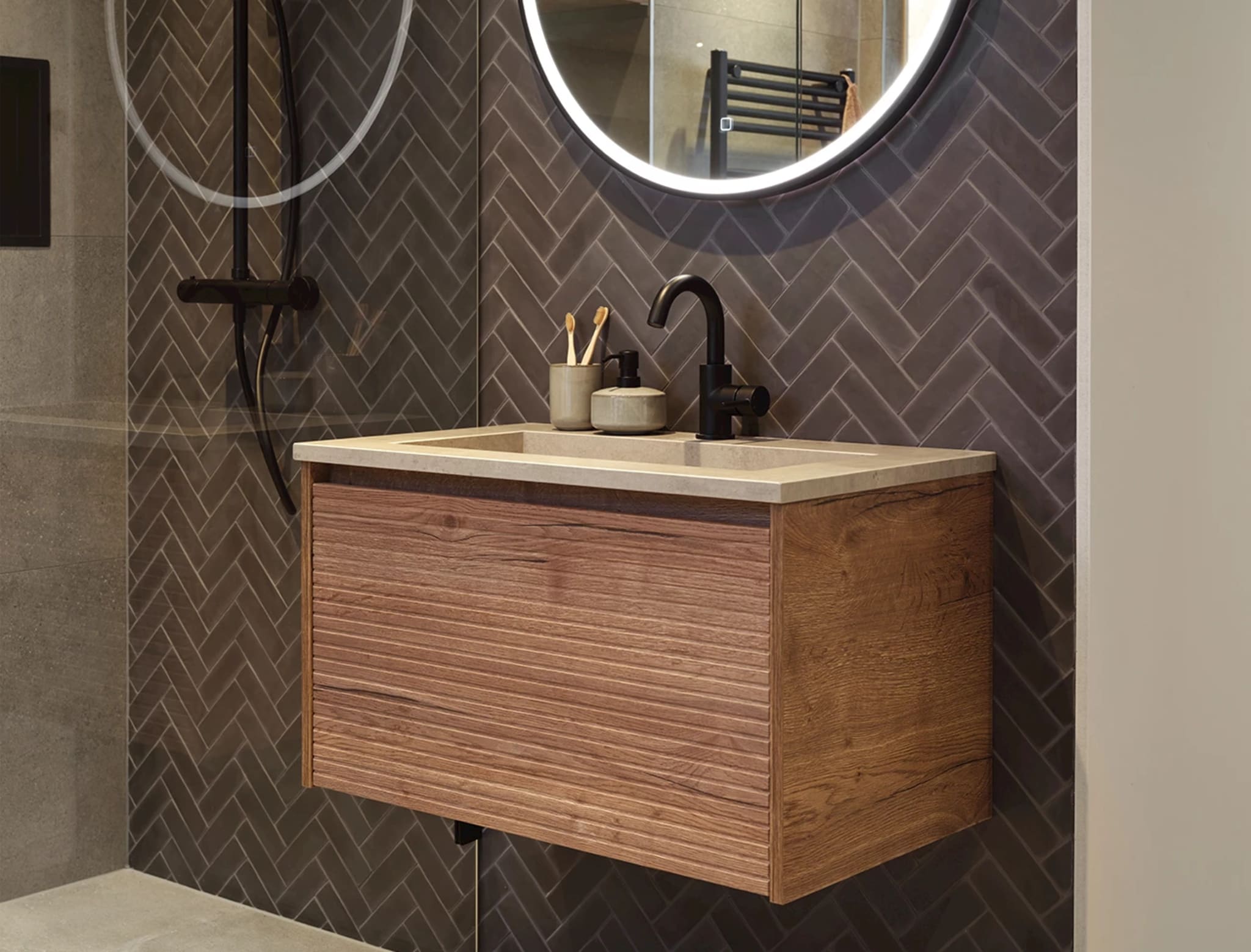 Houtlook badmeubel met ribstructuur en lichte betonlook wastafel met mat zwarte kraan onder de ronde spiegel