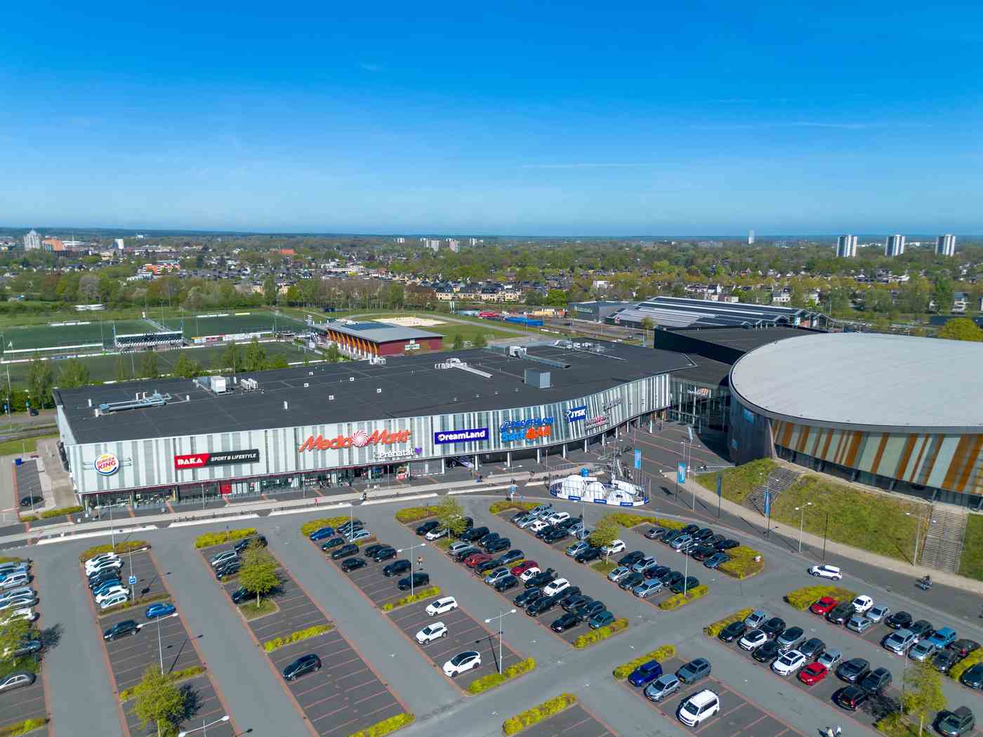 Luchtfoto van het winkelcentrum in Apeldoorn met de Sani4All-winkel tussen onder meer MediaMarkt en DreamLand, met een groot parkeerterrein op de voorgrond
