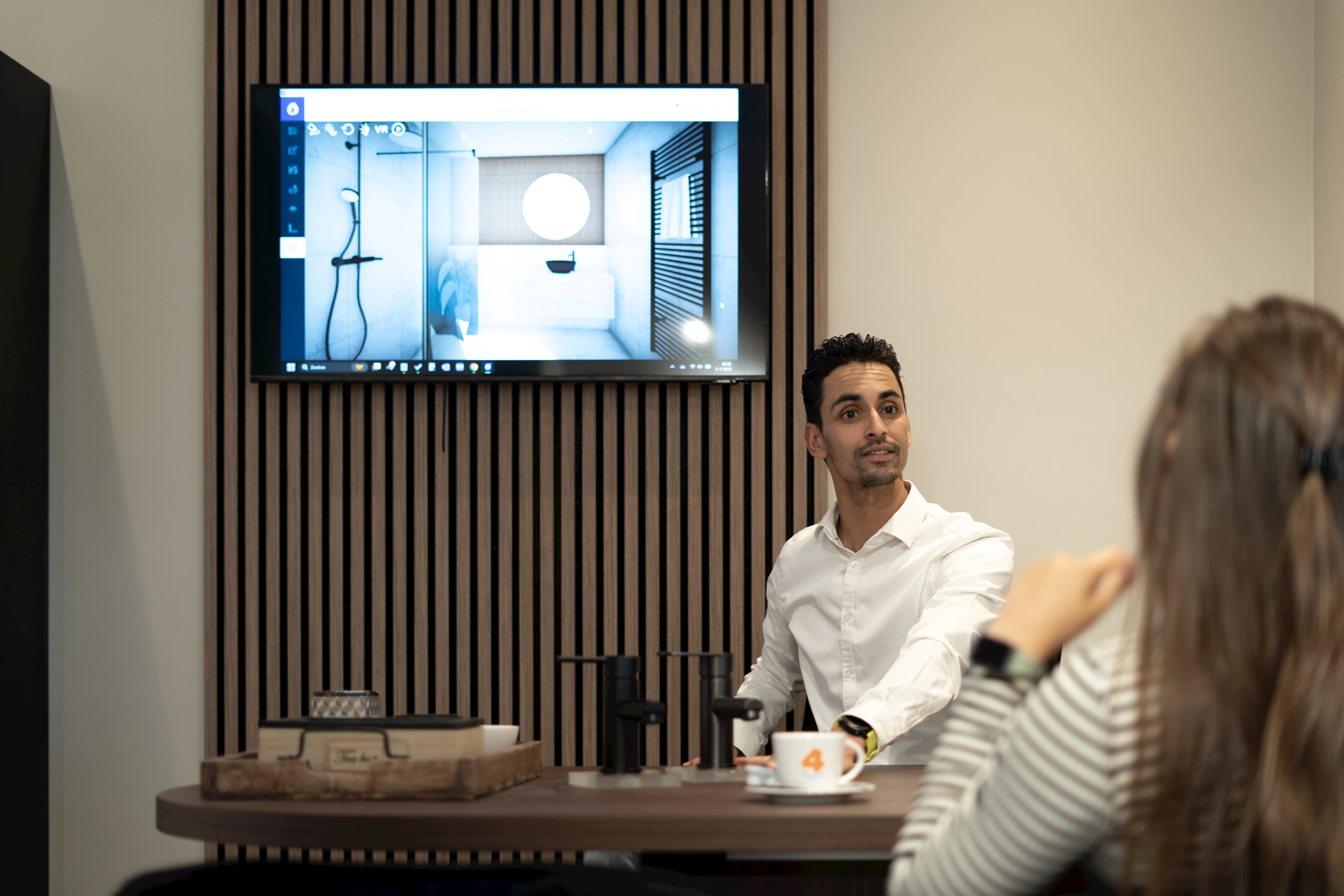 Badkameradviseur bespreekt een 3D-ontwerp met een klant aan tafel