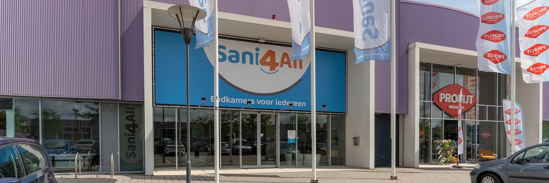 Het winkelpand van Sani4All Gouda met vlaggen bij de entree