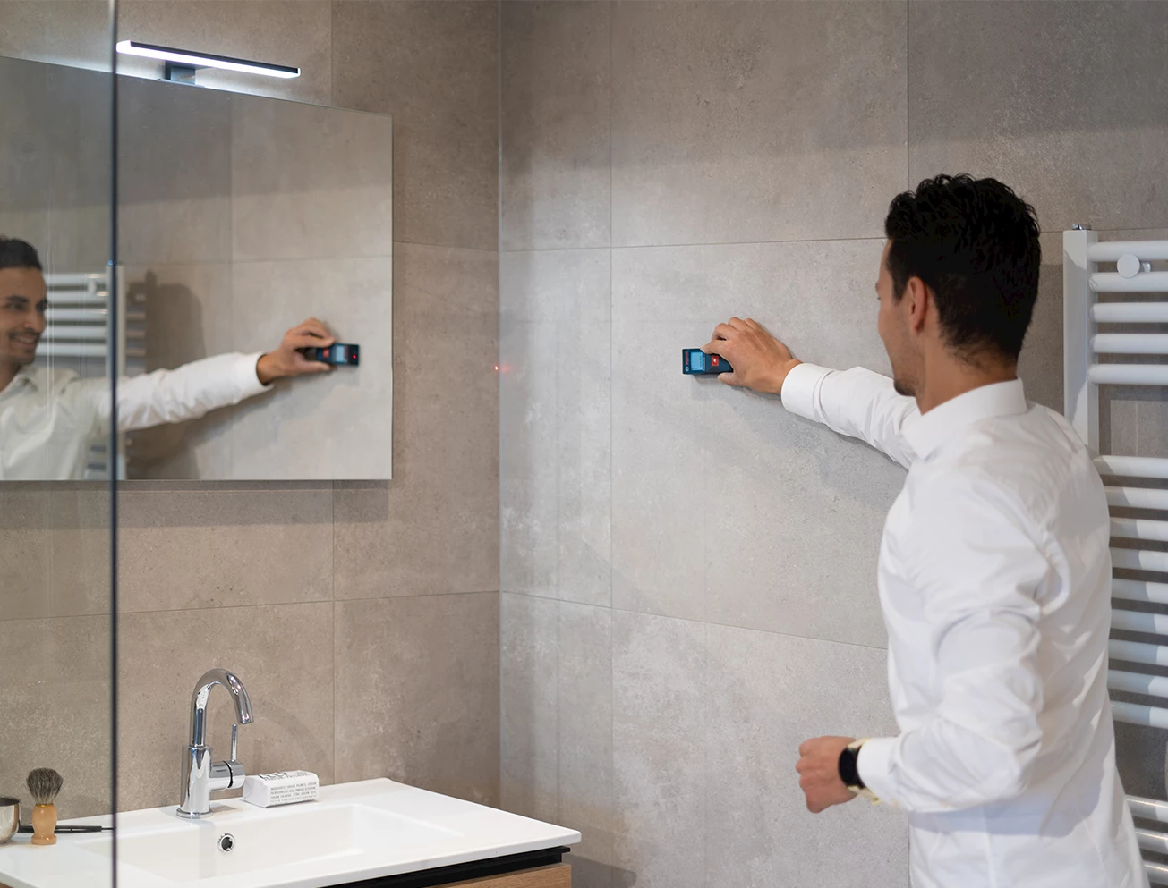 Adviseur meet een badkamer in met een laserafstandsmeter